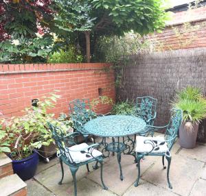 a patio table and chairs with plants and a brick wall at The Coach House Studio Apartment in Leamington Spa
