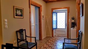 a hallway with two chairs and a door with a window at Yard of Epicurus - Η Αυλή του Επίκουρου in Kato Gatzea