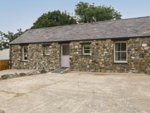 a stone house with a driveway in front of it at Old Shop Cottage in Limavady