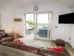 a living room with a leather couch and a sliding glass door at Old Shop Cottage in Limavady