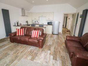 a living room with two leather couches and a kitchen at Old Shop Cottage in Limavady