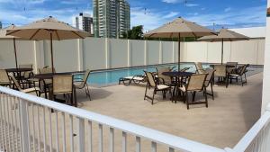 a patio with tables and chairs and umbrellas next to a pool at Casa da Dinda in Ilhéus