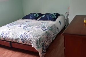 uma cama com lençóis e almofadas azuis e brancos em Agréable logement dans petit village sud-essonne em Champcueil