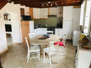 a kitchen with a wooden table and white chairs at Maison tranquillité in Montégut-Plantaurel