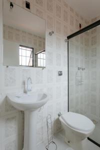 a white bathroom with a sink and a toilet at CASAPERNAMBUCO 100mts da praia in Guarujá +61 photos