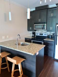 a kitchen with black cabinets and a sink and two stools at Condo Le Champlain-102 in Bromont