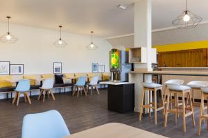 a restaurant with chairs and tables and a bar at Comfort Hotel Amiens Nord in Amiens