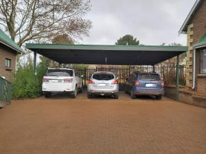 3 auto parcheggiate in un parcheggio vicino a una recinzione di Clarens Mountain Sage Cottage a Clarens