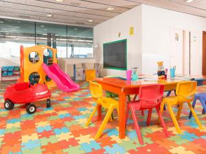 une salle de classe avec une table et des chaises ainsi qu'une aire de jeux dans l'établissement Guitart La Molina Aparthotel & Spa, à La Molina
