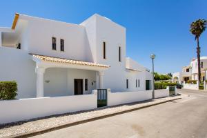 a white house on a street with a palm tree at Casa São Rafael by LovelyStay in Albufeira