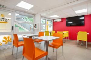 un restaurante con mesas y sillas naranjas y una pared roja en Première Classe Villejust en Villejust