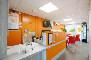 Première Classe Villejust في Villejust: مكتب بجدران برتقالية وجار زجاجي على منضدة