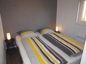 2 camas con mantas a rayas y almohadas en un dormitorio en Vakantiechalet "Huisje onder de Toren" en Oostkapelle