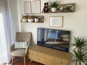 sala de estar con TV de pantalla plana y silla en Casa Poo de Llanes con jardín, en Póo