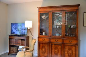 einen Holzschrank mit Glastüren neben einem TV in der Unterkunft Cottage Marie-Henriette in Spa