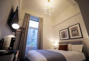 a bedroom with a bed with a chandelier and a window at Boutique 50 in Glasgow +24 photos