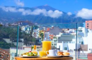 a table with breakfast foods and orange juice on a balcony at DWO Nopal in Puerto de la Cruz