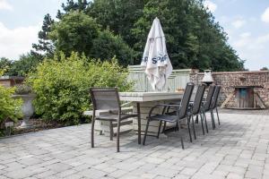 a table with chairs and an umbrella on a patio at Luppolo vakantiehuis Westhoek in Alveringem