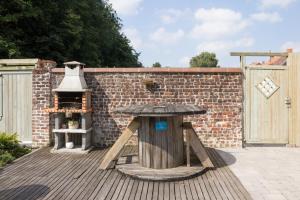 a wooden table on a deck with a brick wall at Luppolo vakantiehuis Westhoek in Alveringem