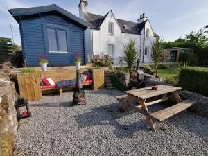 a backyard with a bench and a table and a house at Skye Coorie Cabin in Breakish