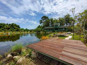 a wooden bridge over a lake in front of a building at บ้านย่า ณ ท่าไทร in Si Racha