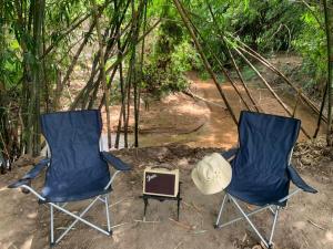 two blue chairs and a hat in the woods at บ้านย่า ณ ท่าไทร in Si Racha