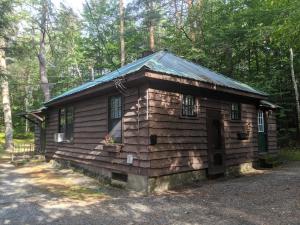 uma pequena cabana de madeira no meio da floresta em Moreno's Cottages em Saranac Lake