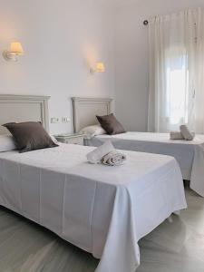 2 letti in una camera con pareti bianche di Hotel Doña Blanca a Siviglia