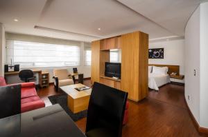 Habitación de hotel con cama y sala de estar. en Travelers Obelisco Apartamentos, en Bogotá