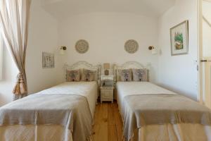 Habitación con 2 camas, paredes blancas y suelo de madera. en Casa do Povo, en Elvas