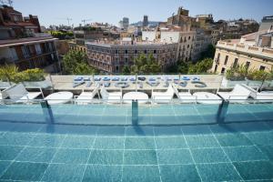 a swimming pool with chairs and a view of a city at Catalonia Eixample 1864 in Barcelona
