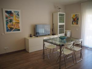a dining room with a glass table and a tv at Apartament per families a Sant Feliu amb piscina in Sant Feliu de Guixols