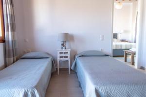 a room with two beds and a table with a lamp at Stefanos Studios in Skala