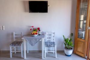 a table with two chairs and a television on a wall at Stefanos Studios in Skala