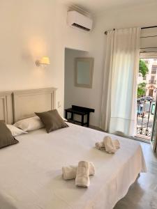 una camera da letto con un grande letto bianco con due asciugamani di Hotel Doña Blanca a Siviglia