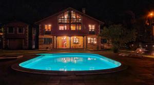 a swimming pool in front of a house at night at Refugio del Cares in Ortiguero