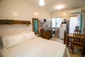 Cet appartement comprend une chambre avec un lit blanc et une cuisine. dans l'établissement Hospedagem Morada Nativa Praia Bombas, à Bombinhas