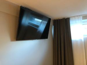einen Flachbild-TV, der an einer Wand neben einem Fenster hängt in der Unterkunft HOSTEL TOIVOLA in Kemi