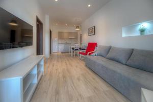 a living room with a gray couch and a kitchen at Apartments Estelle in Pula