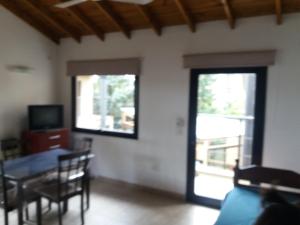 sala de estar con mesa de comedor y ventana en Aylen Departamentos en Pinamar en Pinamar