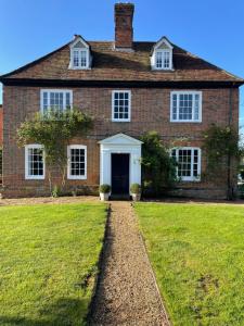 uma grande casa de tijolos com um jardim de relva em Little Park Farm Queen Anne Farmhouse & Apartments em Stratfield Mortimer