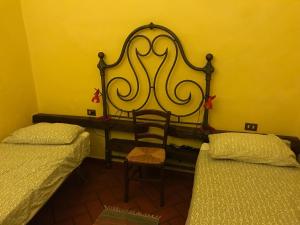 een kamer met 2 bedden en een stoel. bij B&B e Locazioni Turistiche Antico Borgo Toscano in Montecatini Terme