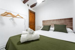 ein Schlafzimmer mit einem Bett mit einer grünen Decke und Handtüchern in der Unterkunft Hauzify I Domus Tarragona in Tarragona