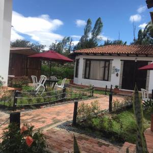 ein Haus mit einer Terrasse und einem Garten mit Stühlen in der Unterkunft Apta villa de leyva in Villa de Leyva