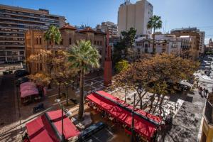 a city street with a red awning and palm trees at Suites Castellón in Castellón de la Plana
