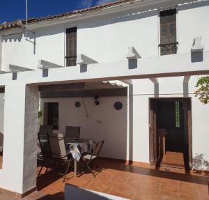 Pinos PuenteにあるCasa Rural Huerta Sarténの白い家で、パティオ(椅子、テーブル付)が備わります。