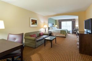 a hotel room with a bed and a living room at Holiday Inn Daytona Beach LPGA in Daytona Beach