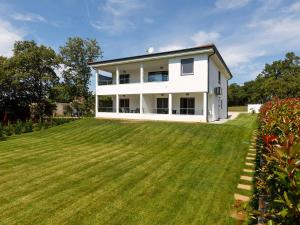 a white house with a large green yard at Apartment Aria in Poreč
