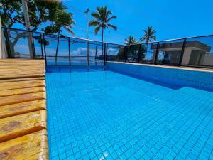 una piscina junto a un complejo con palmeras en Apartamento Paraiso do Pontal, en Ilhéus