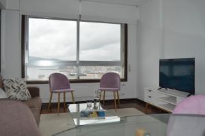 a living room with two purple chairs and a television at Fantástica vista de la Ría de Vigo en pleno centro in Vigo